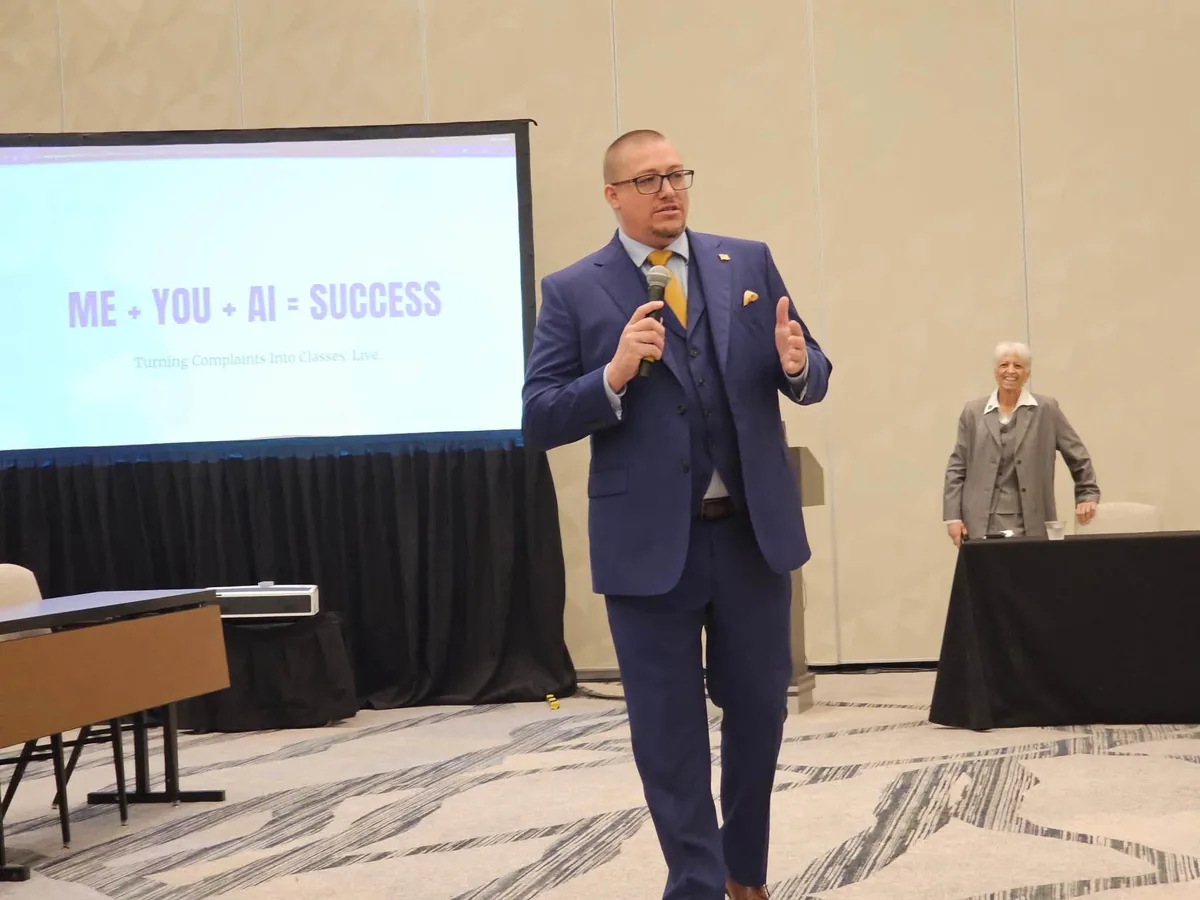 Robert Lee presenting in a three-piece suit beside a slide reading ME + YOU + AI = SUCCESS